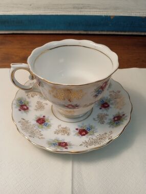 Elegant White Porcelain Teacup and Saucer with Red Floral Accents and Gold Trim